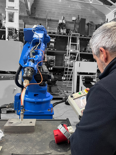 Un robot industrial con aplicación de soldadura programado por un técnico de semapro