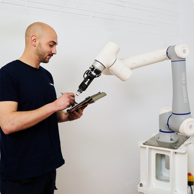 Técnico de empresa de robots colaborativos haciendo el mantenimiento de un cobot de pinza de la marca dobot